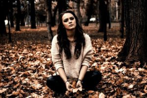 girl sitting alone in the leaes